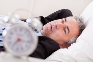 Alarm Clock In Front Of Man Sleeping